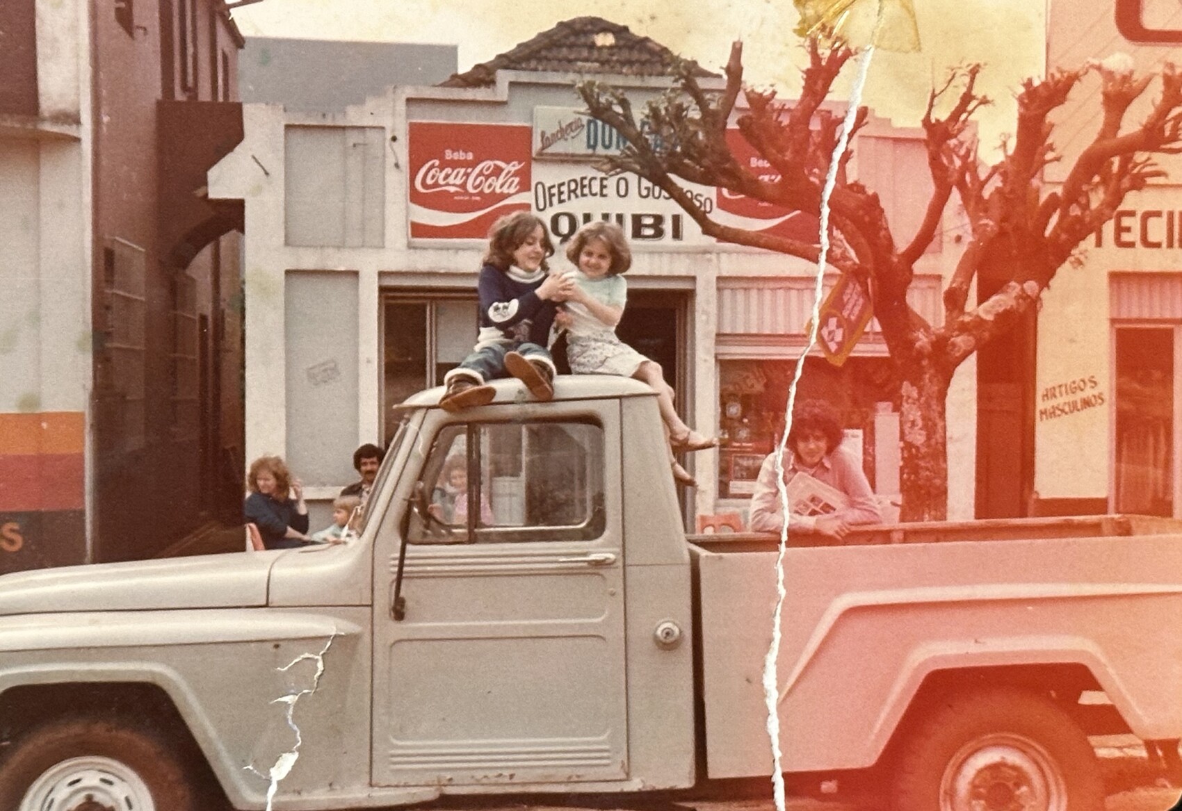 Restaurante da fam&iacute;lia em 1980, com Ali e Mariana ao fundo e Nasser na camionete, e a fachada anunciando: oferece o gostoso quibi